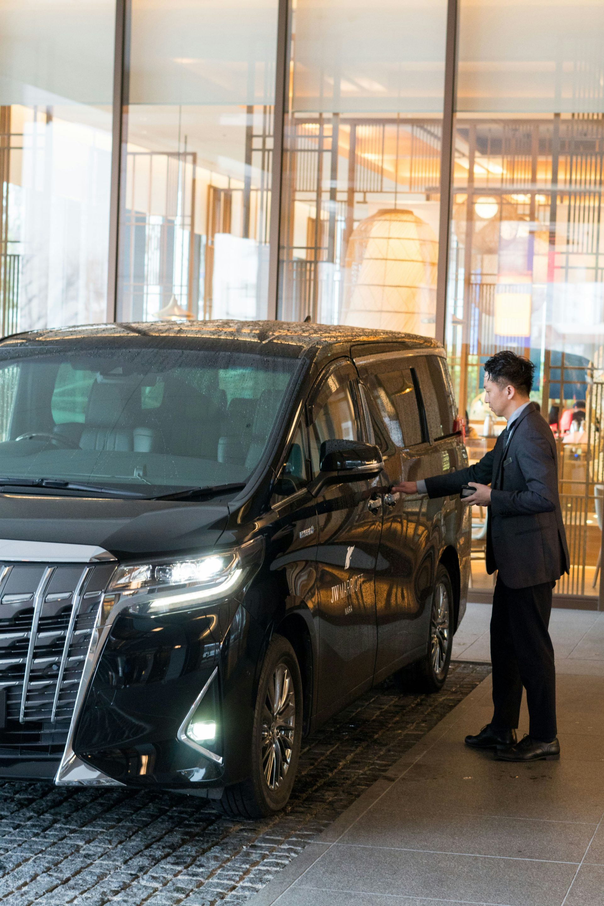 A man in a suit standing next to a black car